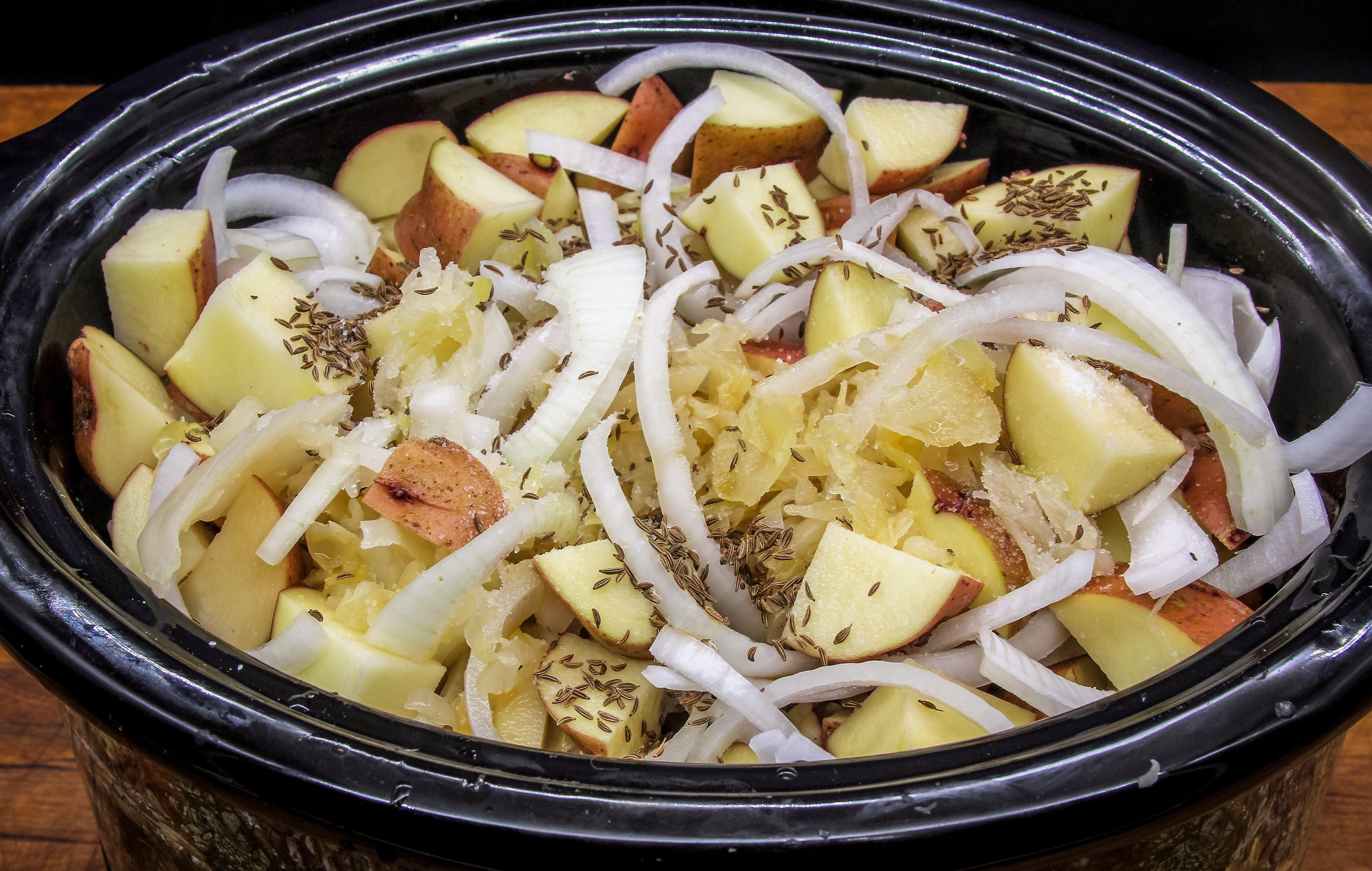 Add the seared venison, sauerkraut, potatoes, onions and seasonings to the slow cooker.