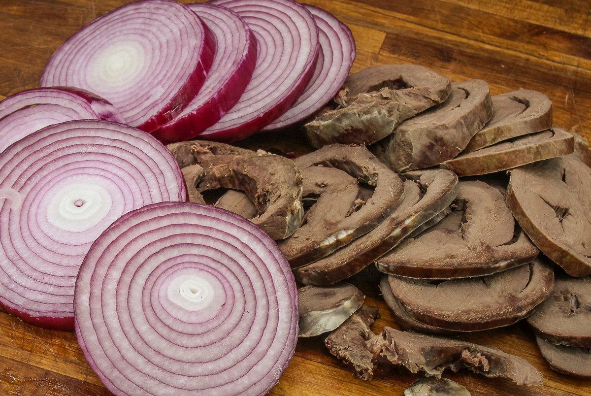 Slice the red onion and simmered deer heart thinly before adding to the jar.