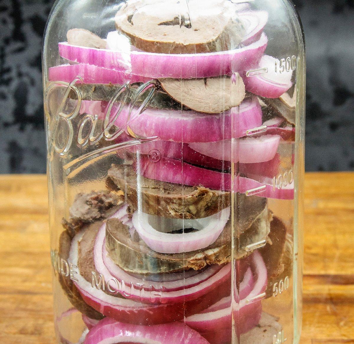Layer the heart and onion in a clean jar before pouring over the pickling brine.
