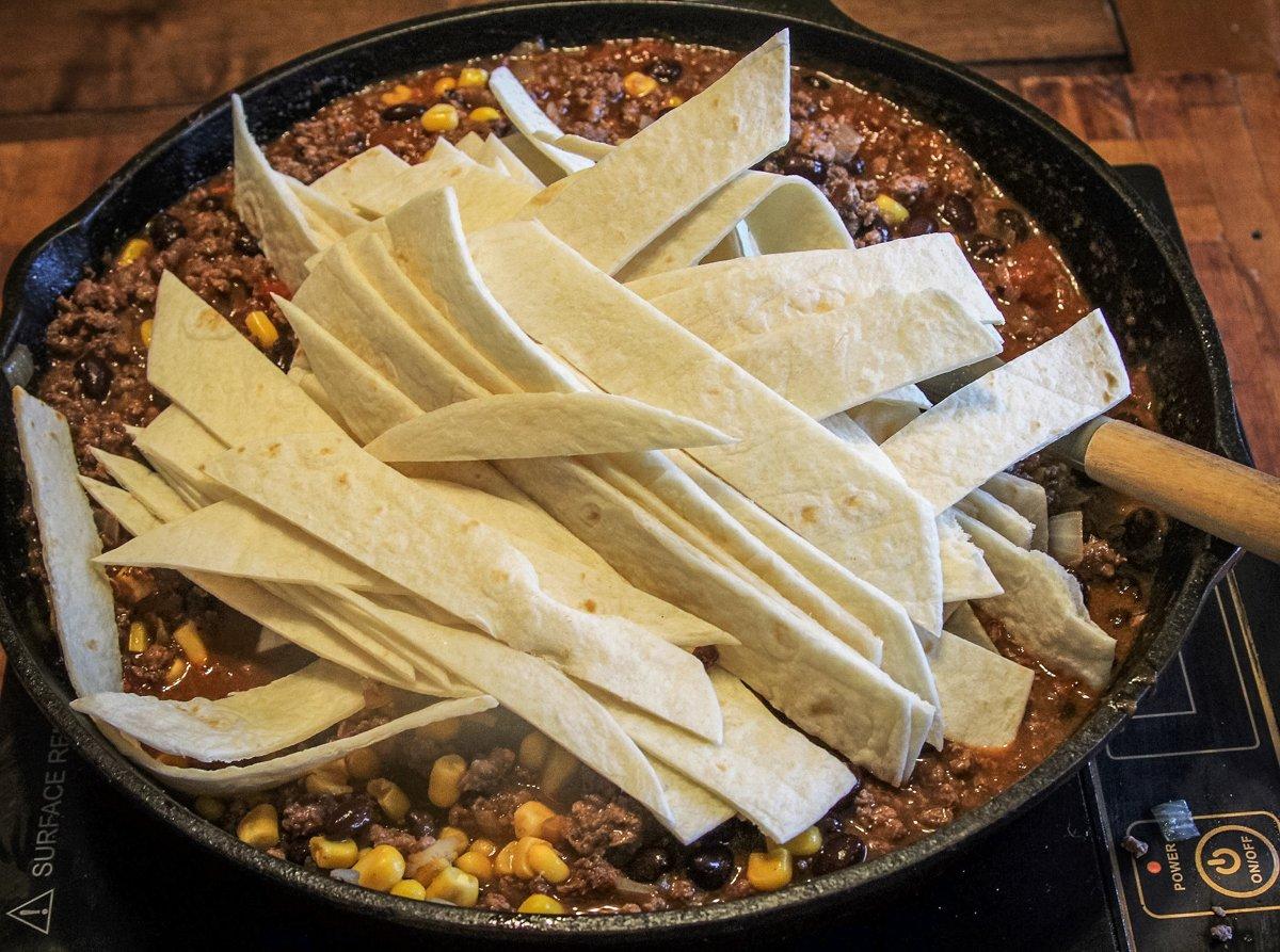 Add the tortilla strips to the skillet and stir to blend them in.