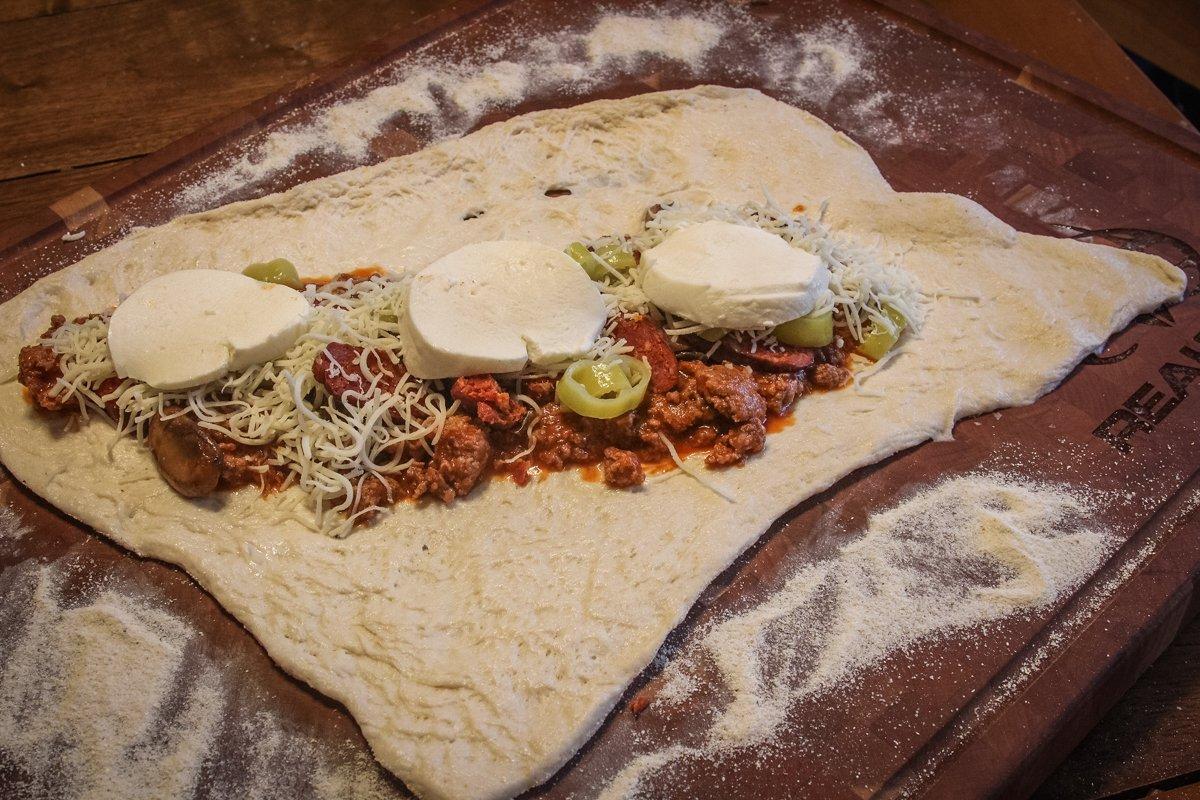 Spoon the meat sauce onto the center of the dough, then pile on the toppings.