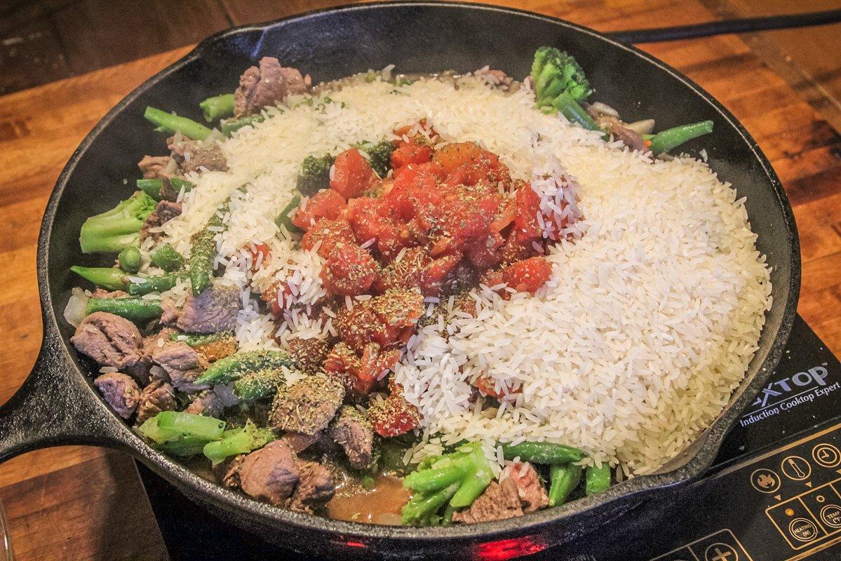 Add the vegetables, tomatoes and uncooked rice to the skillet.