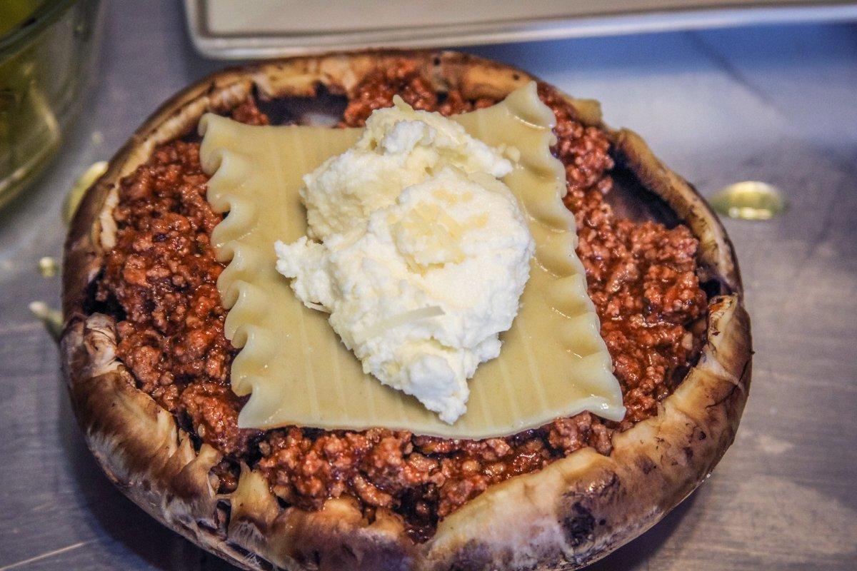 Top the meat sauce with a section of lasagna noodle and a spoonful of ricotta cheese.