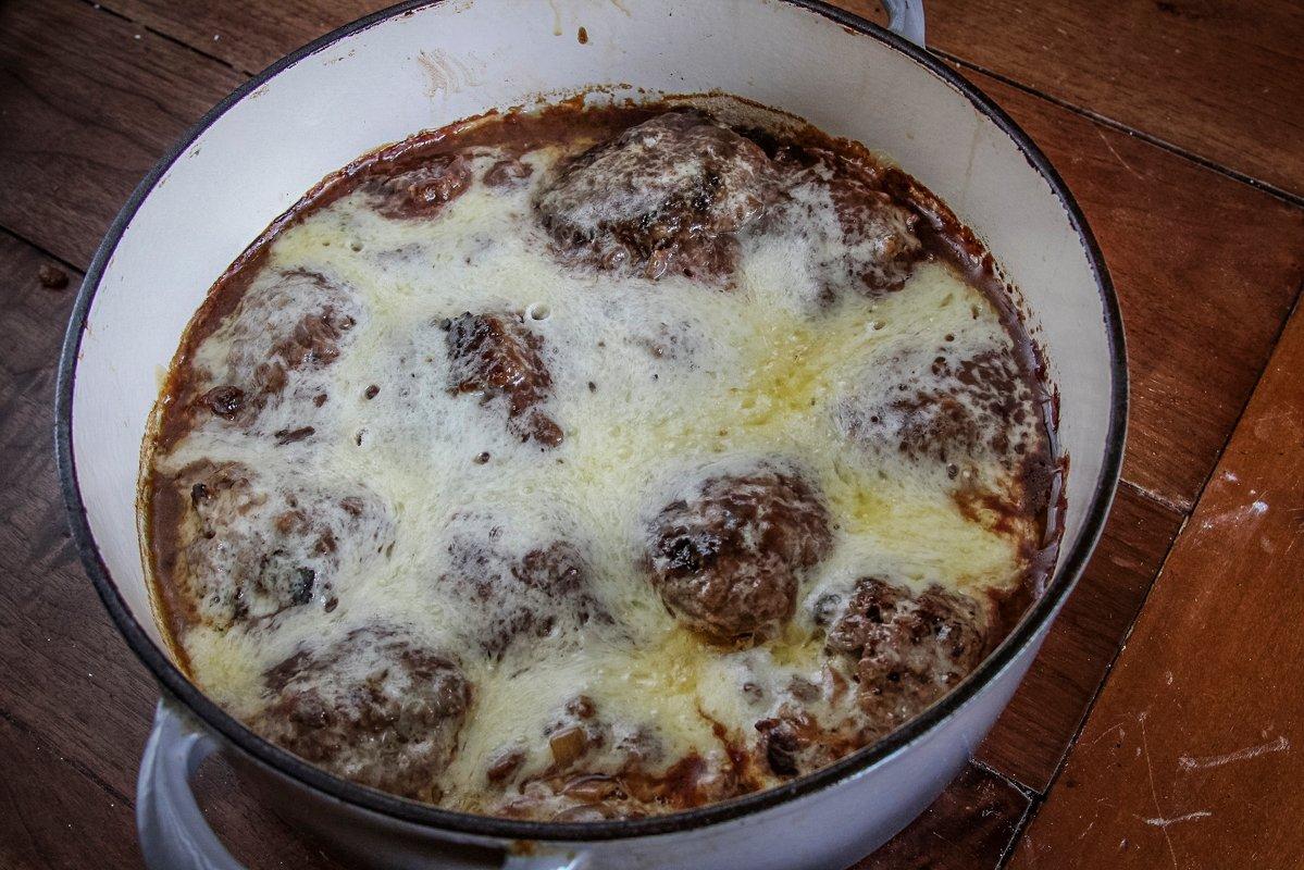 Nestle the meatballs into the onion gravy, top with more cheese, then bake.
