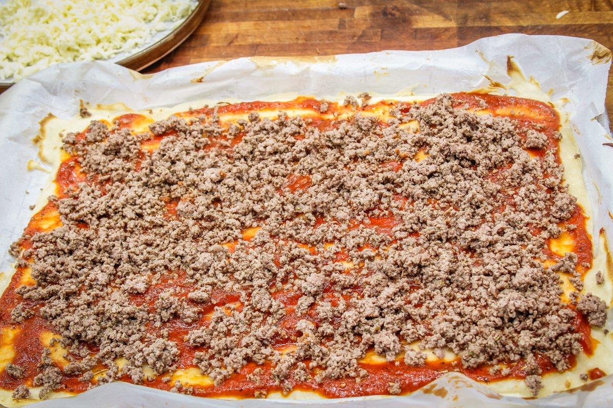 Sprinkle the seasoned browned venison evenly over the pizza crust.