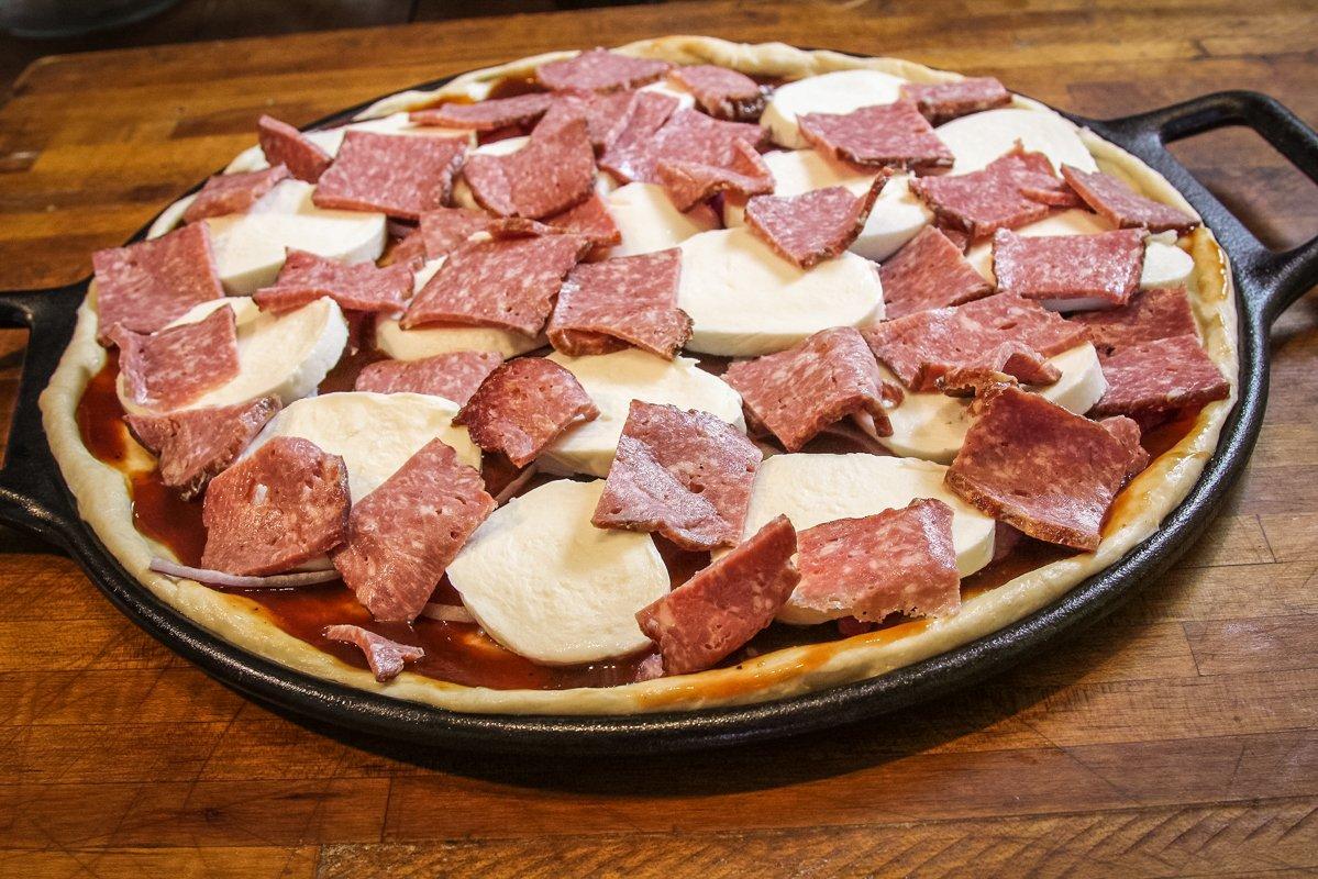 Top the pizza with the onion, bacon, and sliced whole milk mozzarella cheese.