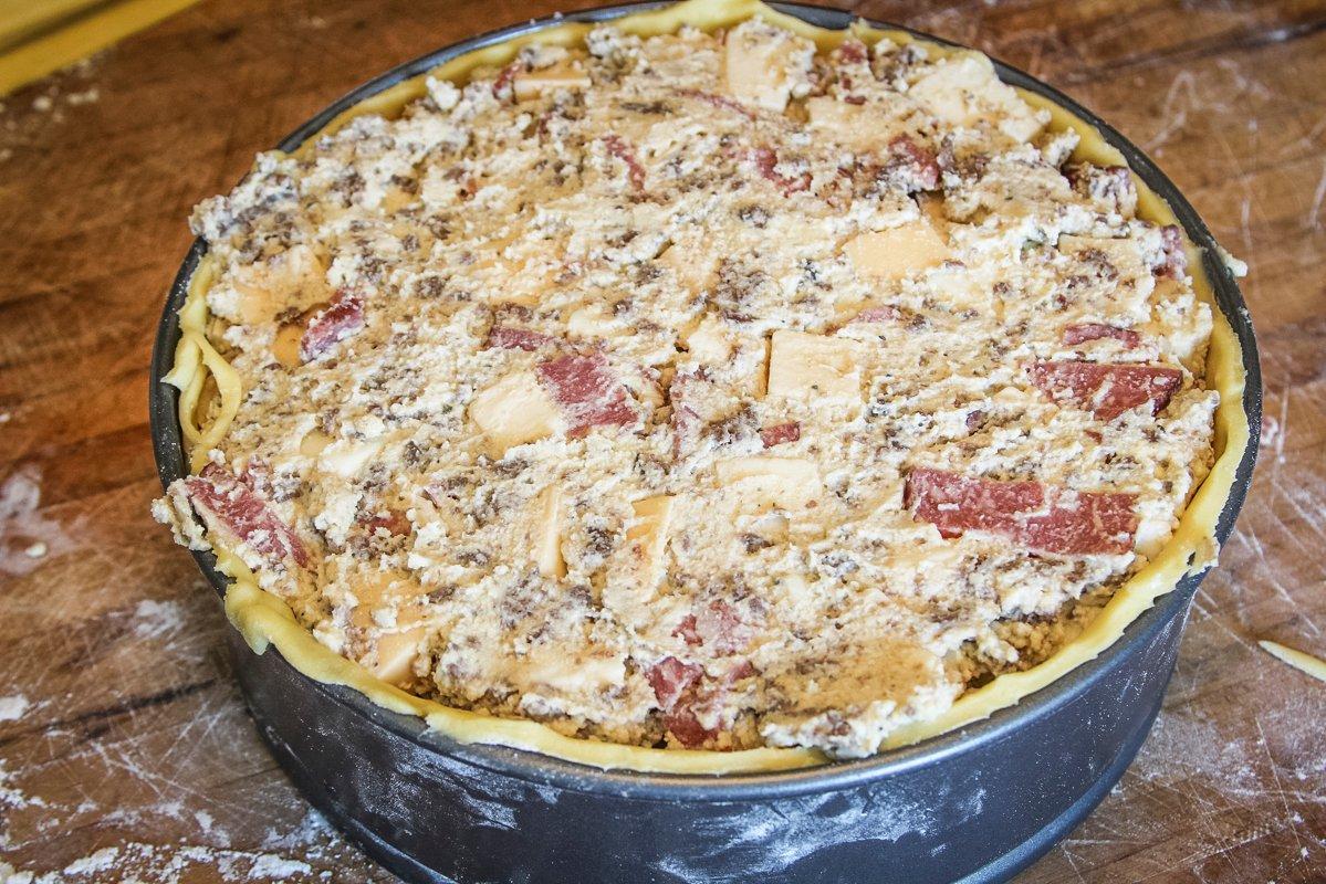 Fill the dough-lined pan with the cheese and meat mixture.