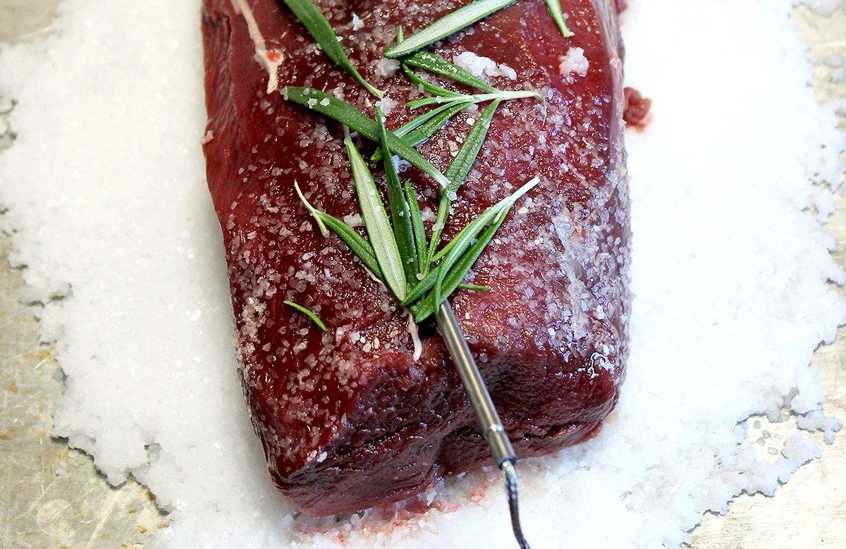 Place the fresh rosemary on top of the venison before covering with salt.