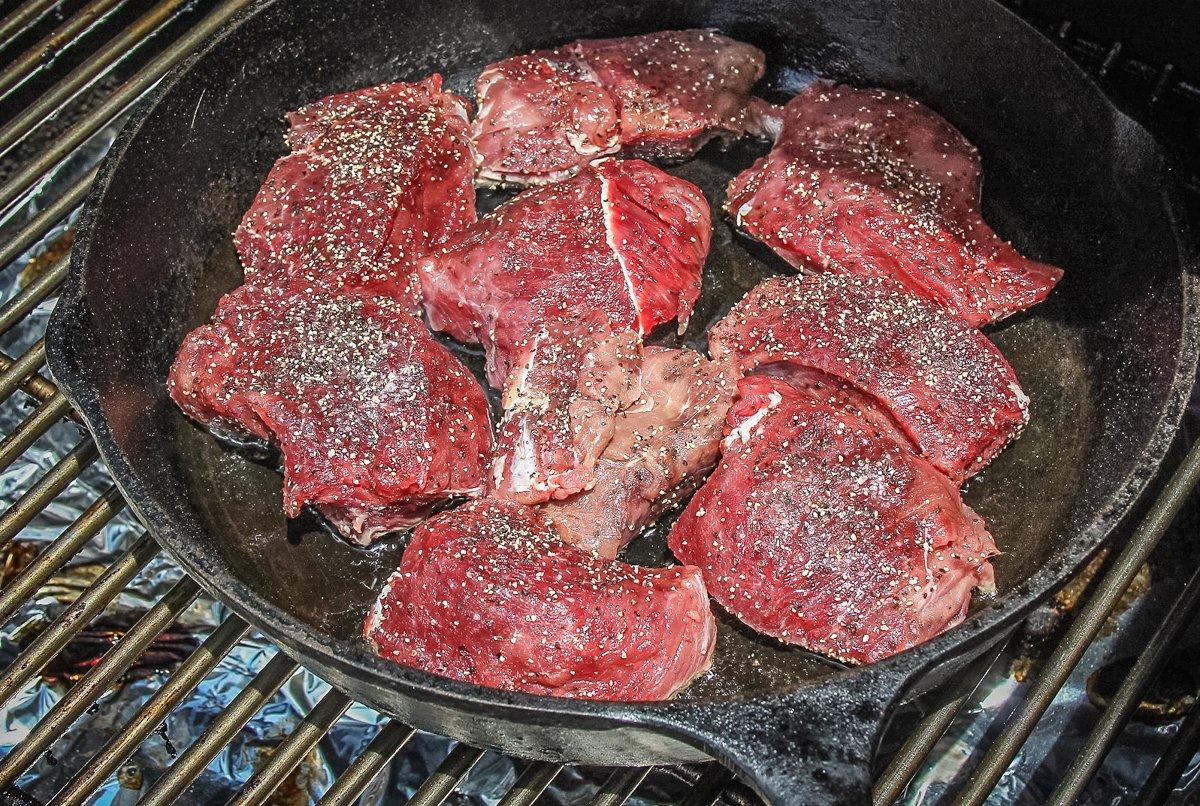 Sear the seasoned backstrap medallions in a pre-heated cast-iron pan on the grill.