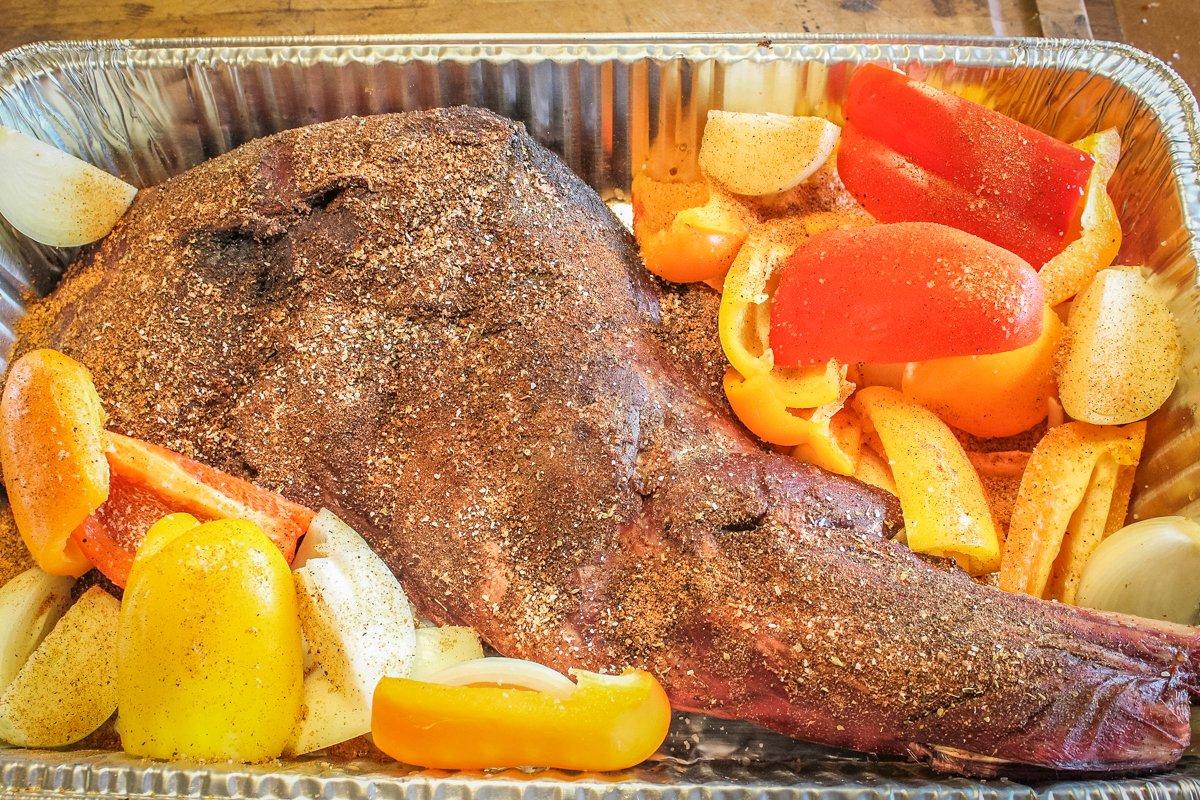 After smoking the shoulder for a few hours, add it to the pan with the peppers and onions.