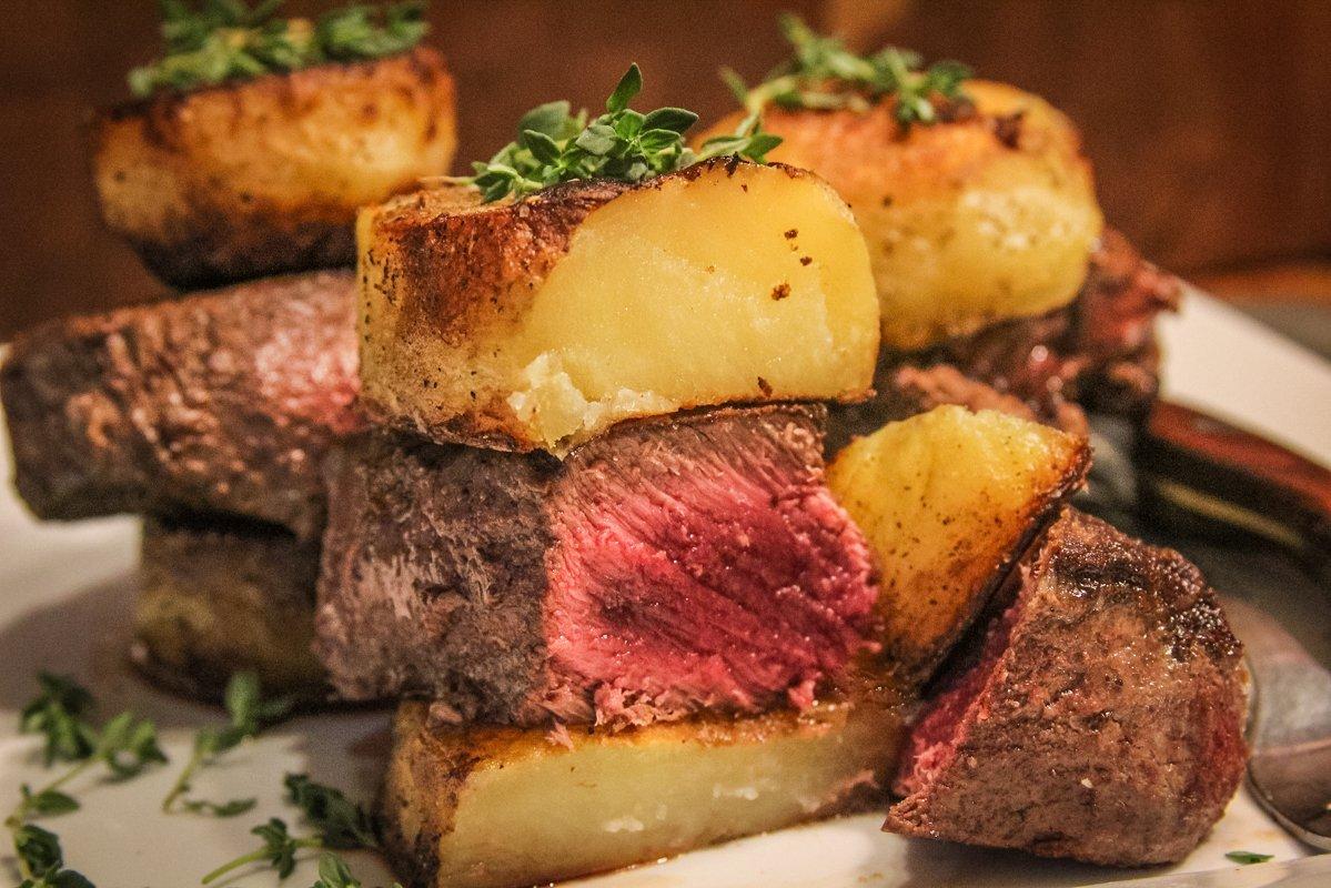 To serve, stack a creamy slice of potato above and below a steak, then top with fresh thyme.