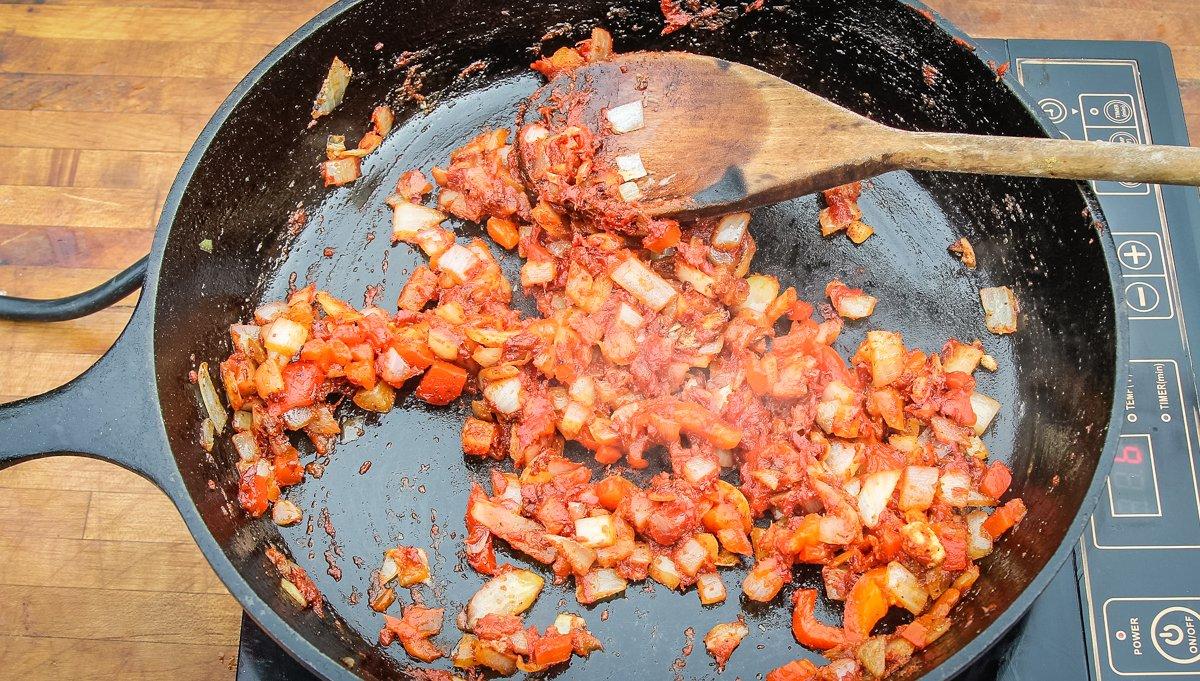 Start by softening onions, then adding seasonings, peppers, and tomato paste.