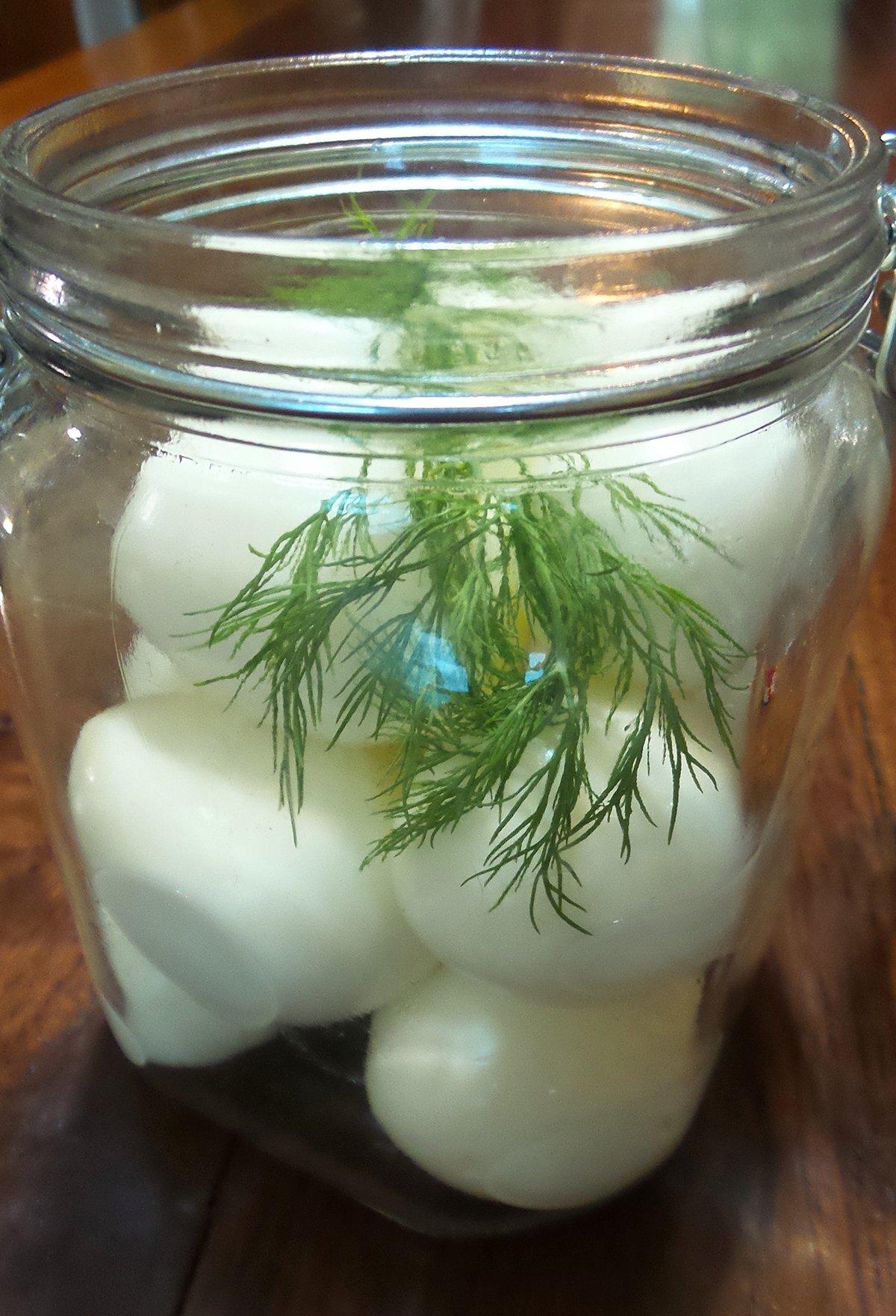 Pack the hard boiled eggs into a jar, about a dozen to a quart, and drop in a sprig of dill.