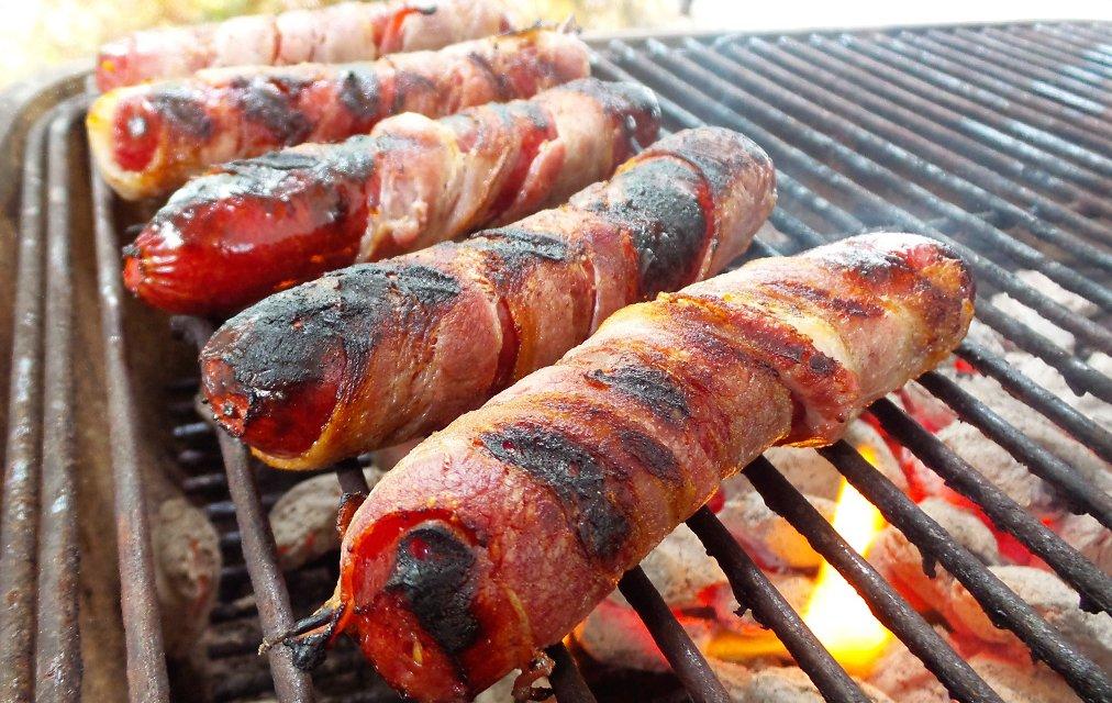 Wrap the sausages in bacon and grill until the bacon is crisp and brown.