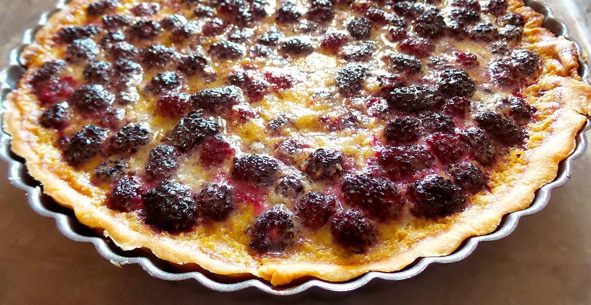The tart filling rises slightly as it bakes, forming a creamy layer around the blackberries.