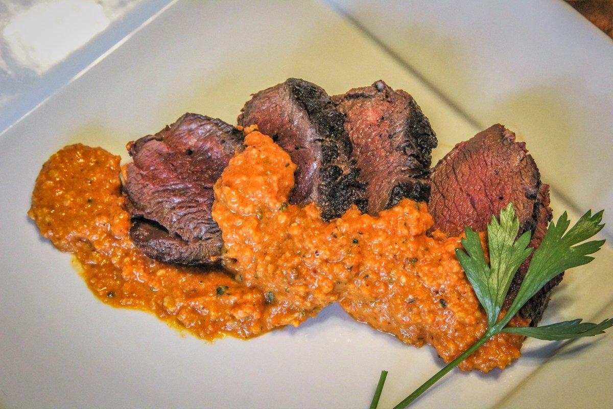 Spoon the Romesco over the sliced venison.