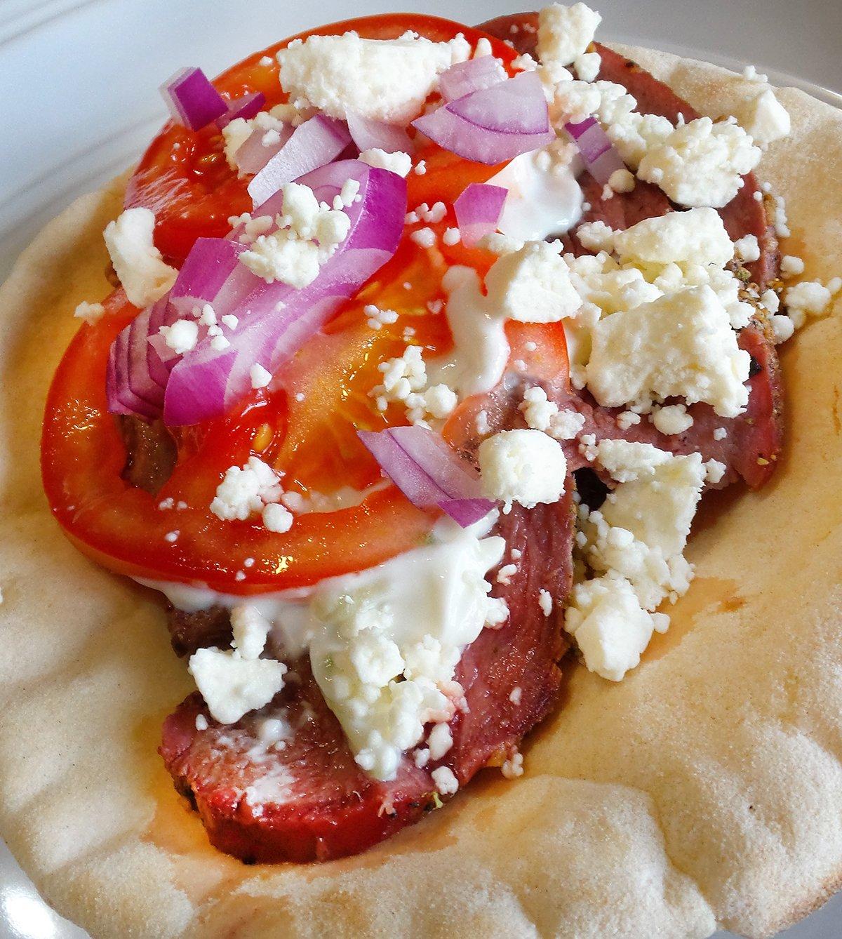 Layer the seasoned meat on a piece of warm pita bread and top with tomatoes, sliced onions and feta cheese.