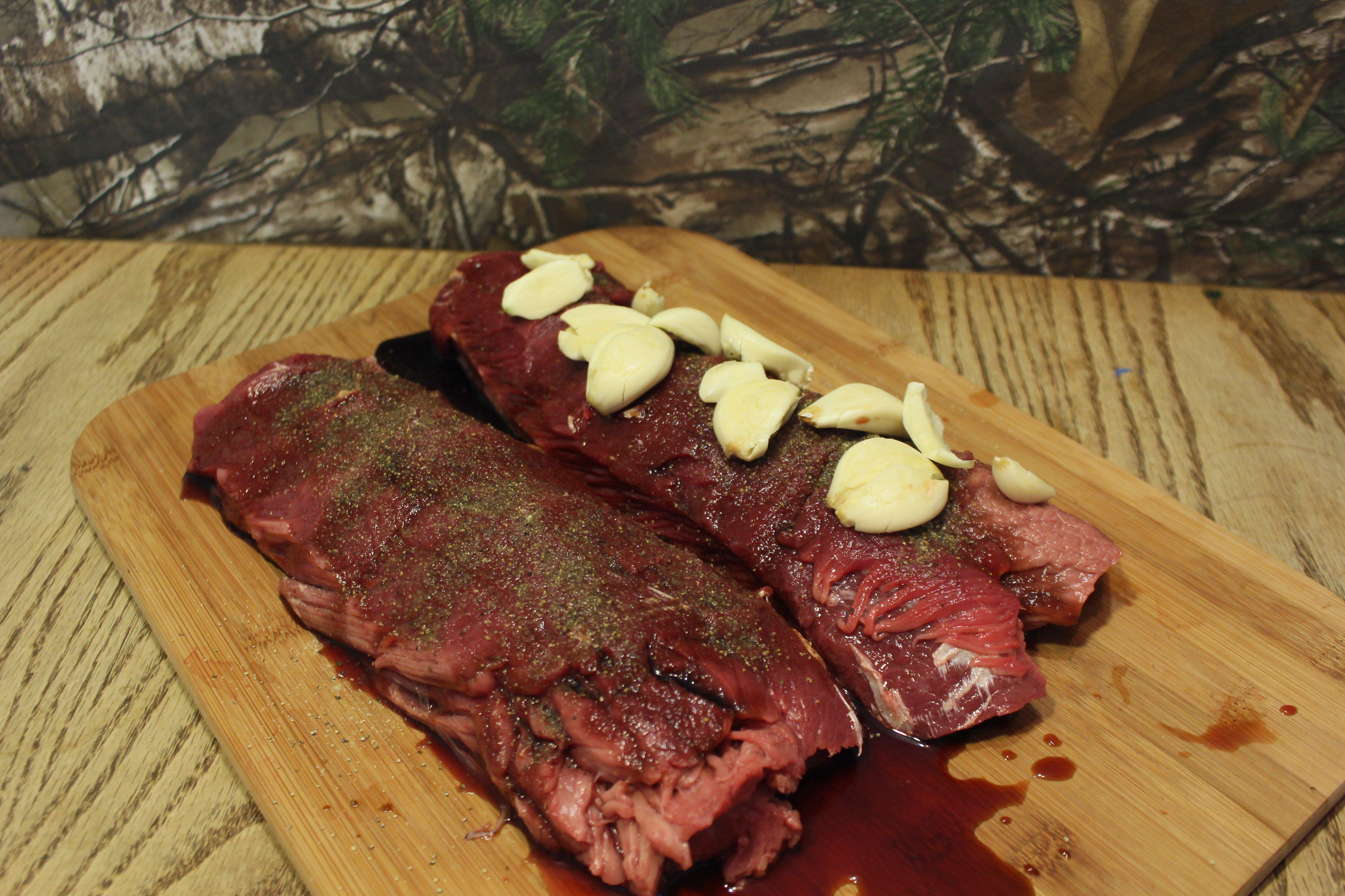 Spread the crushed garlic cloves evenly between the backstrap layers.