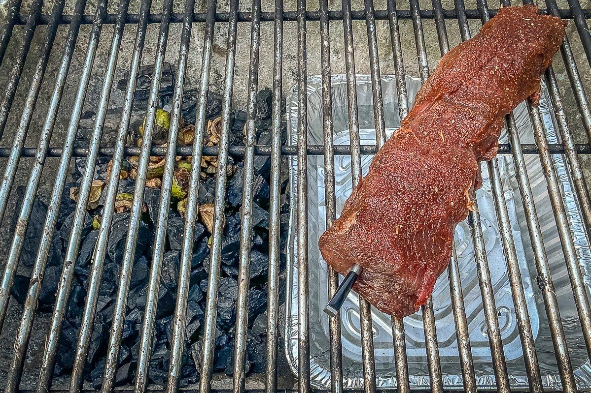 I like to use a two-zone cooking setup with coals on one side of the grill and a water pan under the meat.