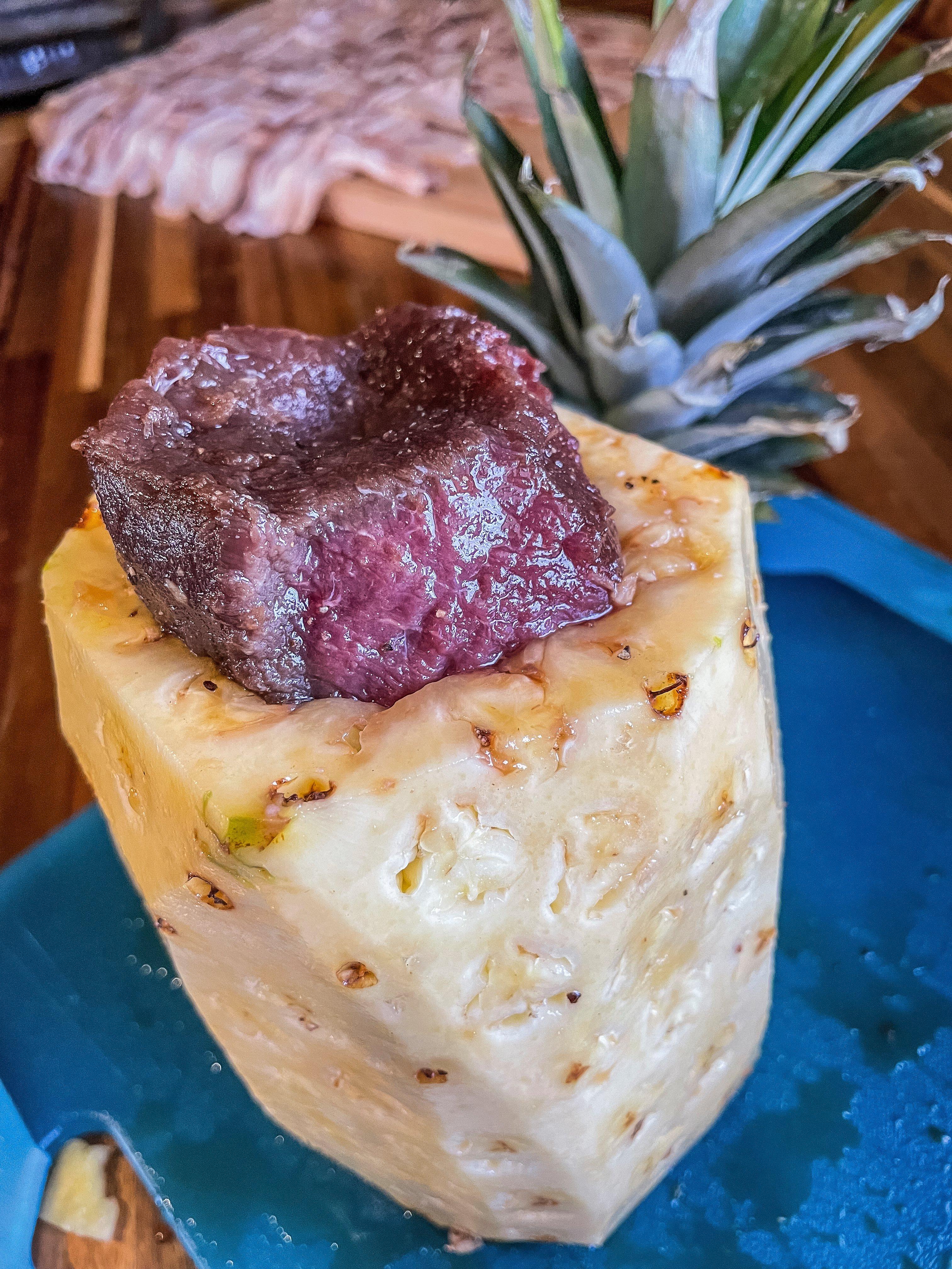 Stuff the seasoned backstrap into the cored and peeled pineapple.