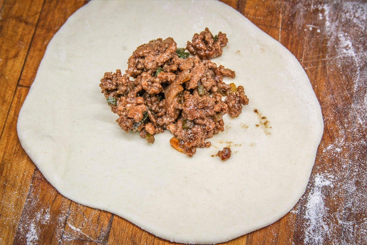 Spoon filling into the center of each round of dough.