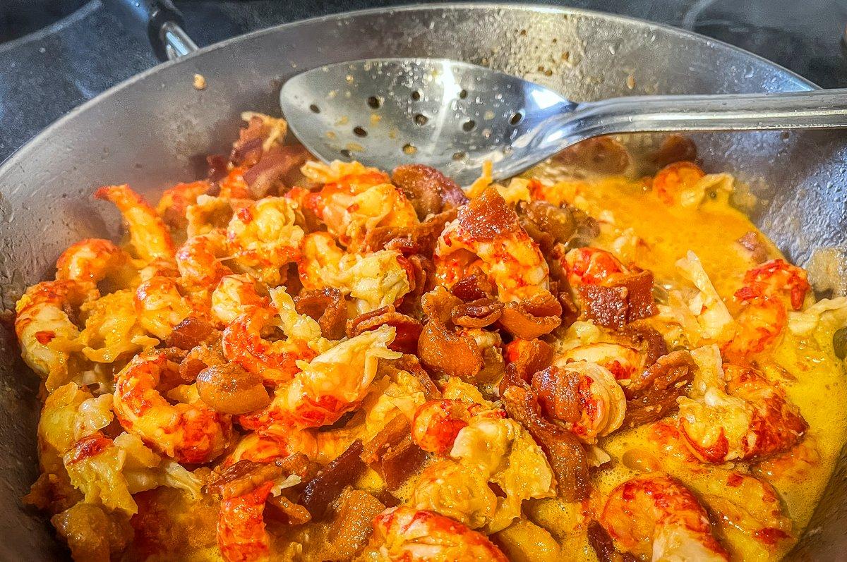 Heat the crawfish tails in the bacon grease, then add the crispy bacon bits back to the pan.