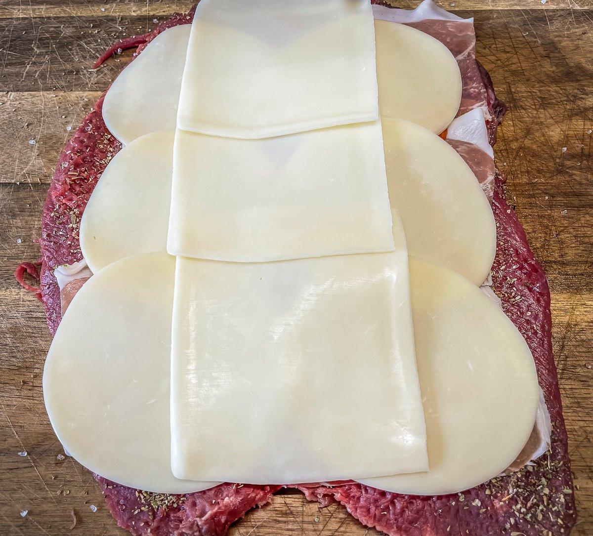 Top the meat with sliced provolone and mozzarella cheese.