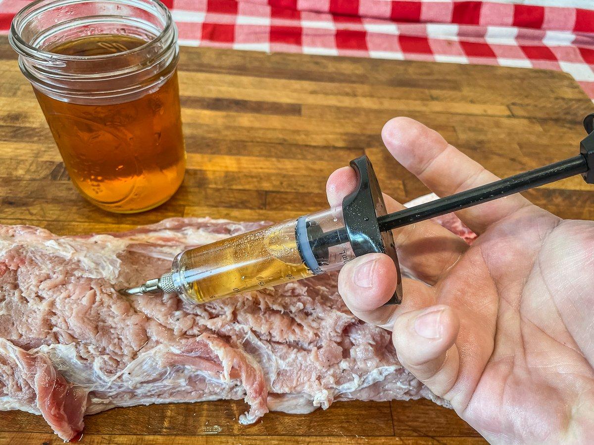 Inject the pork all over with both melted butter and apple cider.