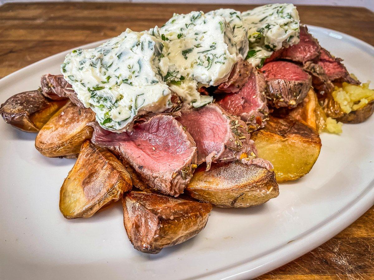 Serve the grilled and sliced backstrap atop roasted potatoes and top everything with the chimichurri butter.