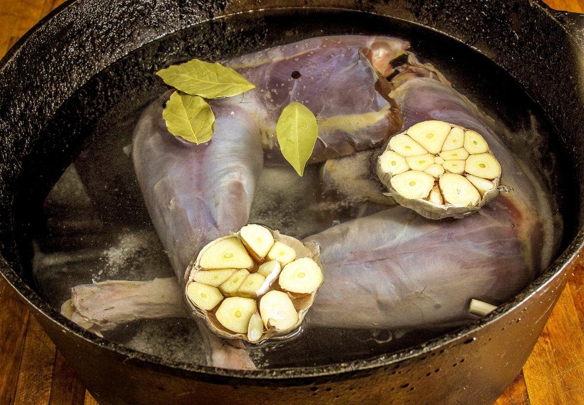 Simmer the turkey legs with garlic, bay leaves, salt, and peppercorns.