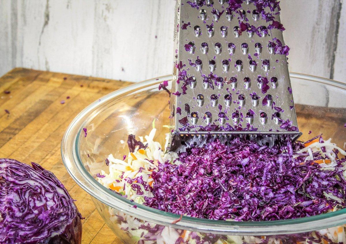 Shred fresh cabbage for the slaw mixture.