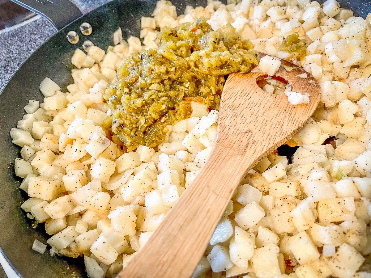 Cook the potatoes and the diced onion, then add the roasted green chile peppers.