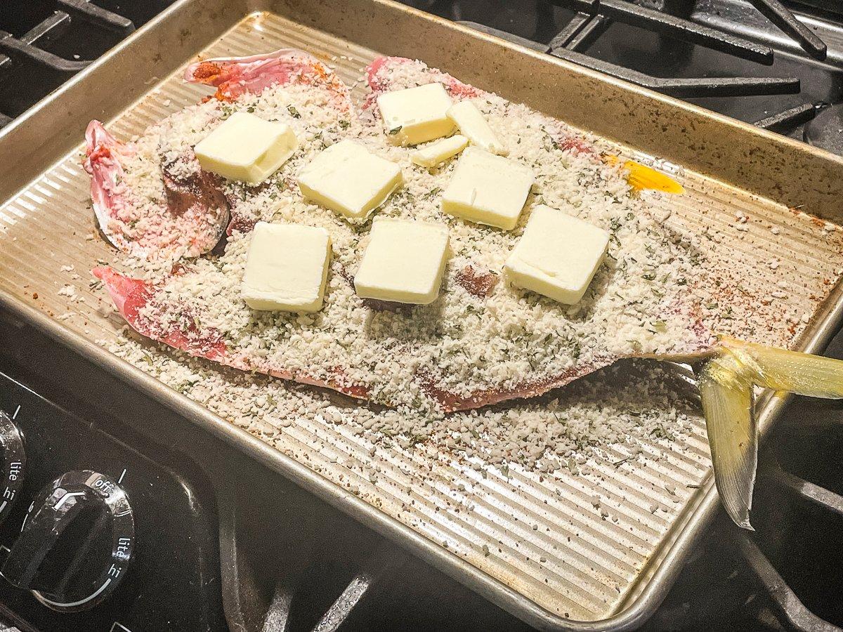 Top the fish with mixed bread crumbs and parmesan cheese, then add butter.