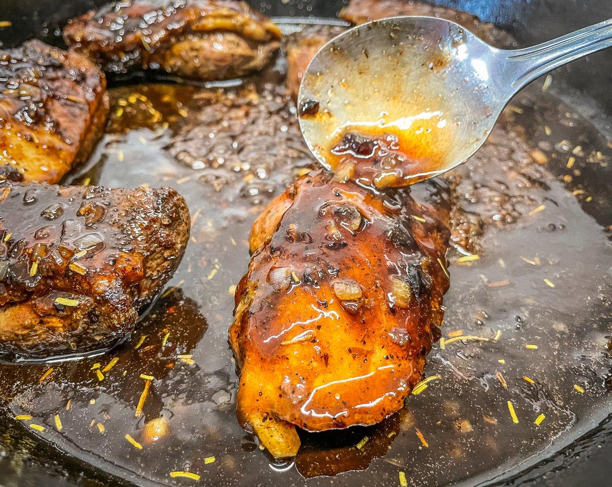 Return the seared breasts to the pan, then spoon over the bourbon plum sauce to coat.