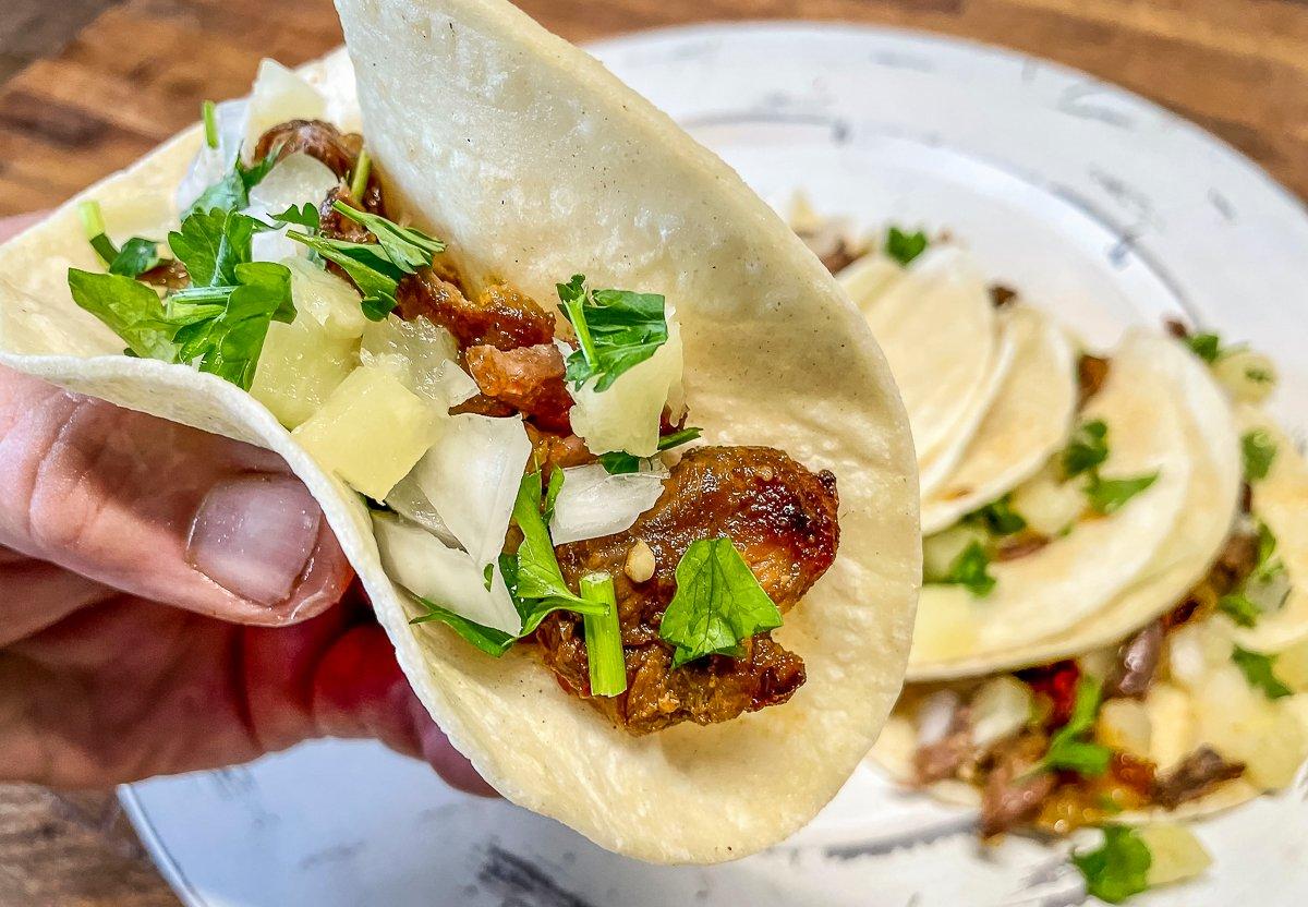 Top the tacos with onion, pineapple, and cilantro.
