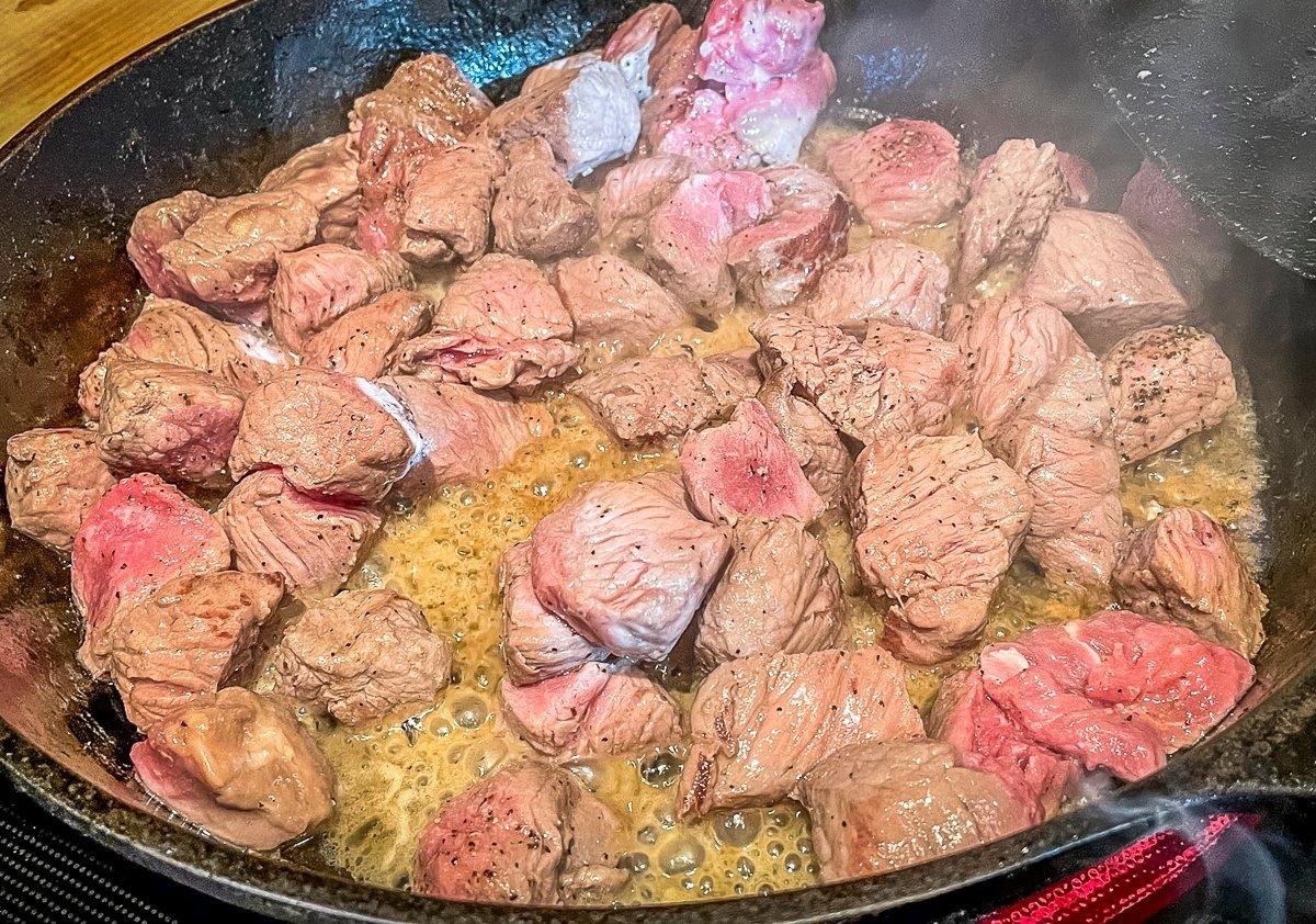 Brown the steak tips in butter, but take care not to overcook them.