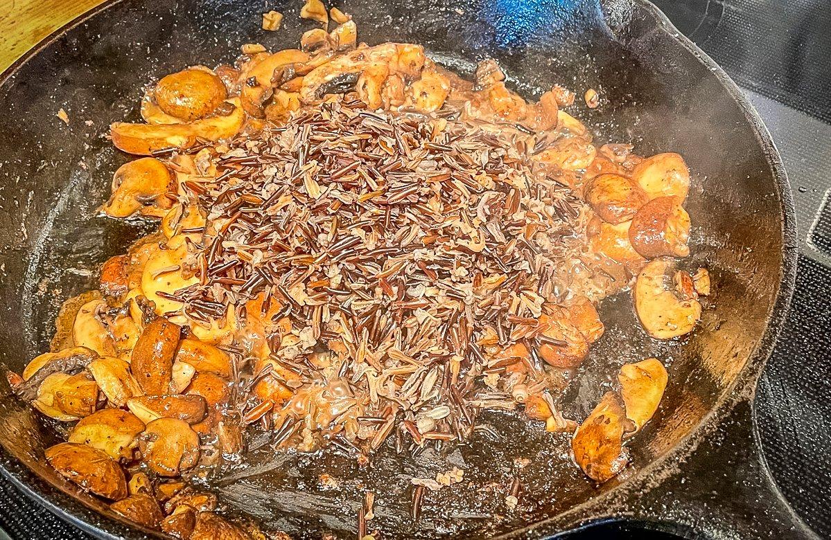 Sauté the mushrooms, then add the cooked wild rice to the pan before deglazing with cider.