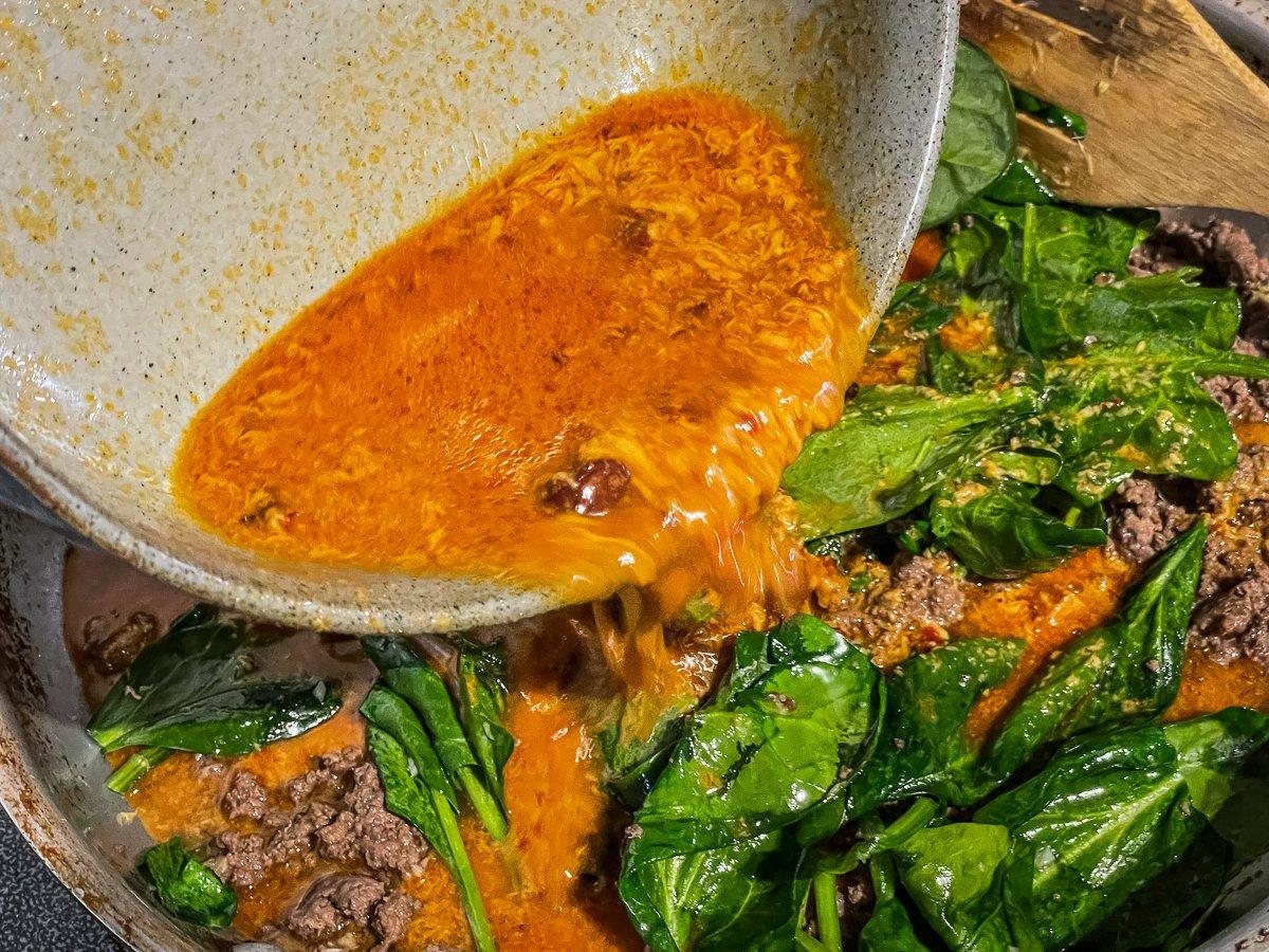 Once the meat and spinach have cooked, stir in the sauce.