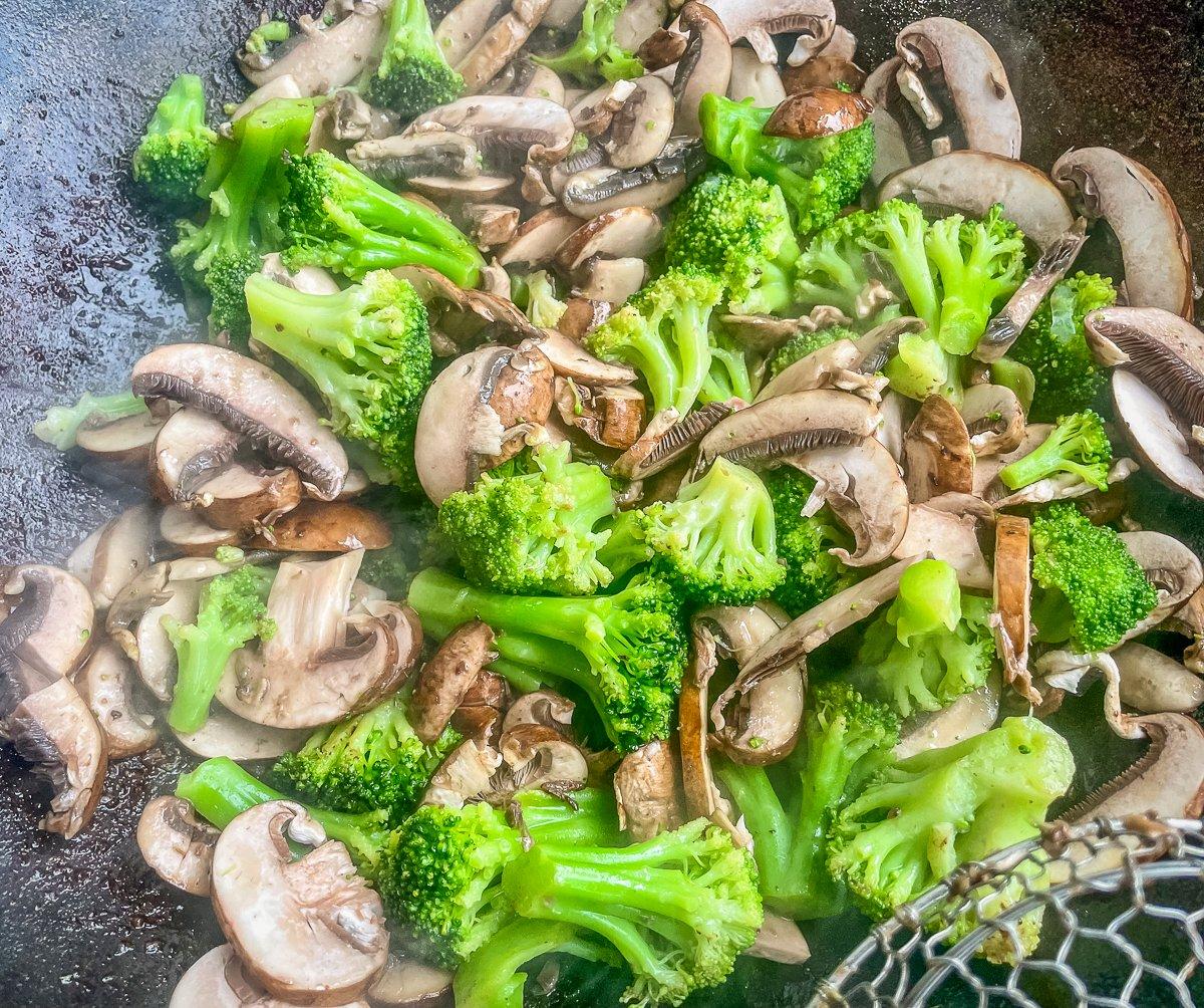 Return the meat to the cooked broccoli and mushrooms.