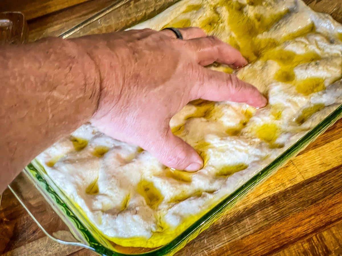 Spread the dough in an olive oiled pan and press dimples with your fingers.