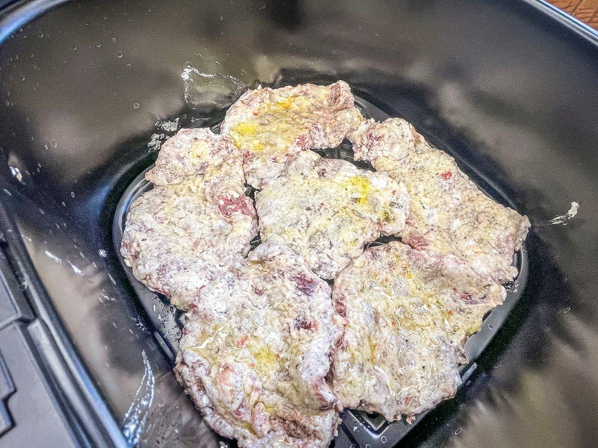 Add the coated steaks to the air fryer basket.