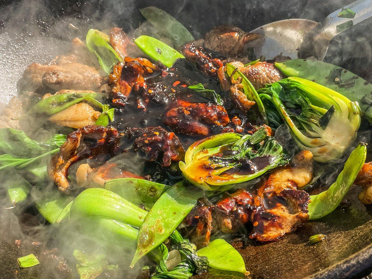 Add the sauces and seasonings to the vegetables and return the meat to the wok.