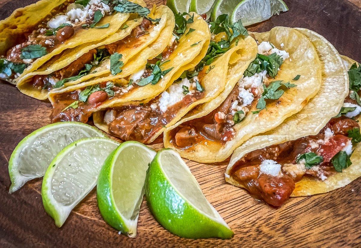 Serve the tacos with lime wedges, crumbled cheese, and chopped cilantro for garnish.