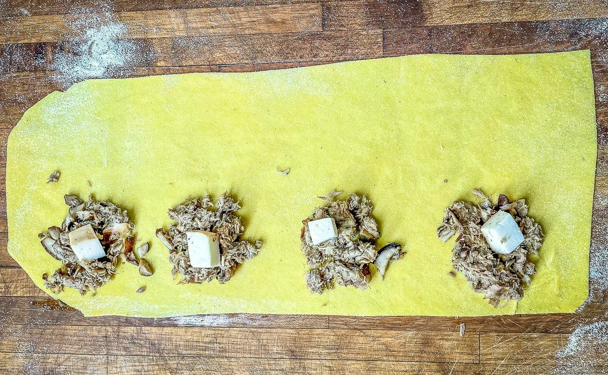 Make small mounds of filling and cheese along one edge of the pasta sheet.