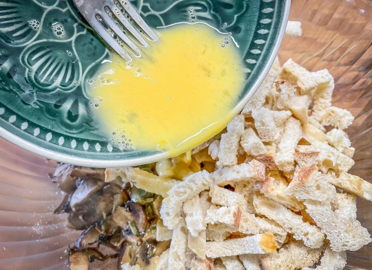 Add the bread cubes, broth, and beaten egg to the cooled mushroom mixture.