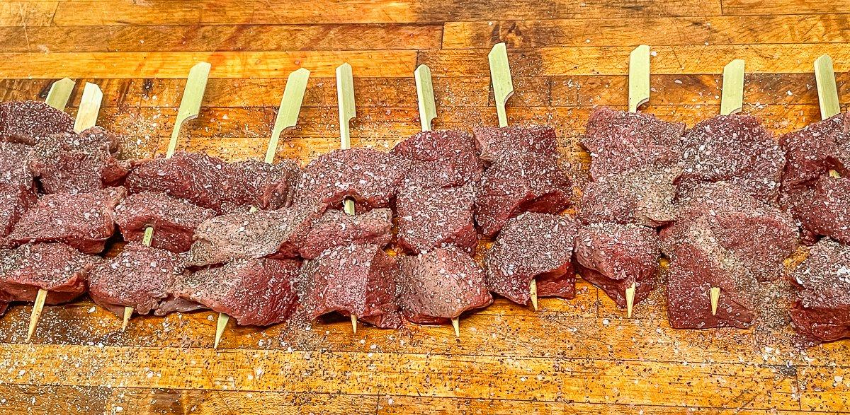 Season the backstrap and thread onto wooden skewers, if desired.