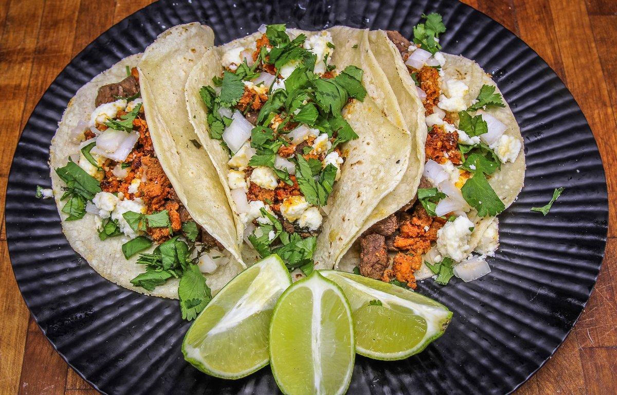 Pile the tacos with venison and chorizo, then top with diced onion and fresh cilantro. 