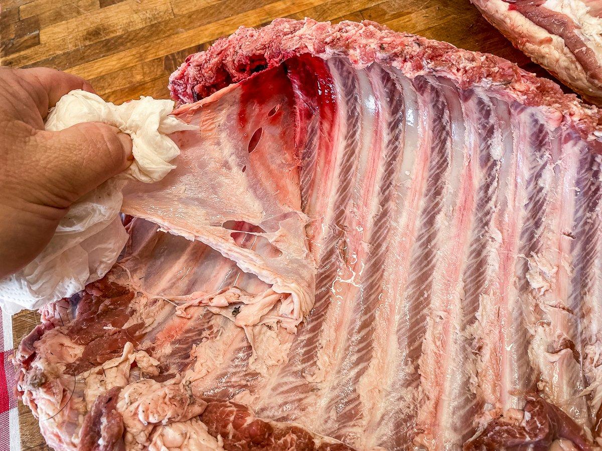 Use a paper towel or a table knife to work the membrane away from the inner side of the ribs.