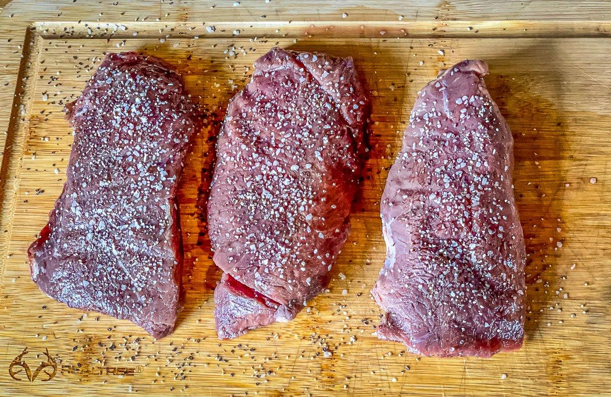 Season the elk steaks on both sides.