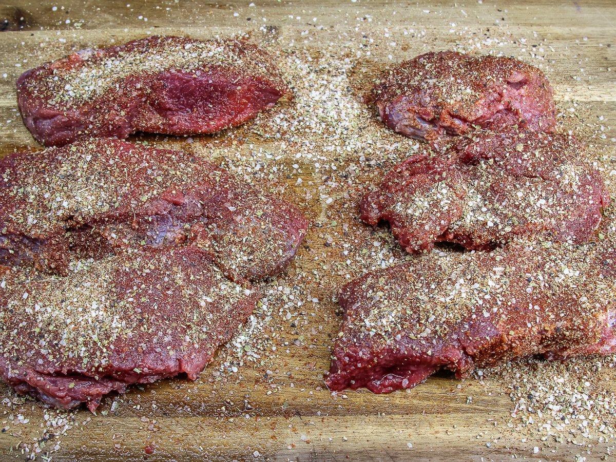 Apply the seasoning blend to both sides of the backstrap steaks.